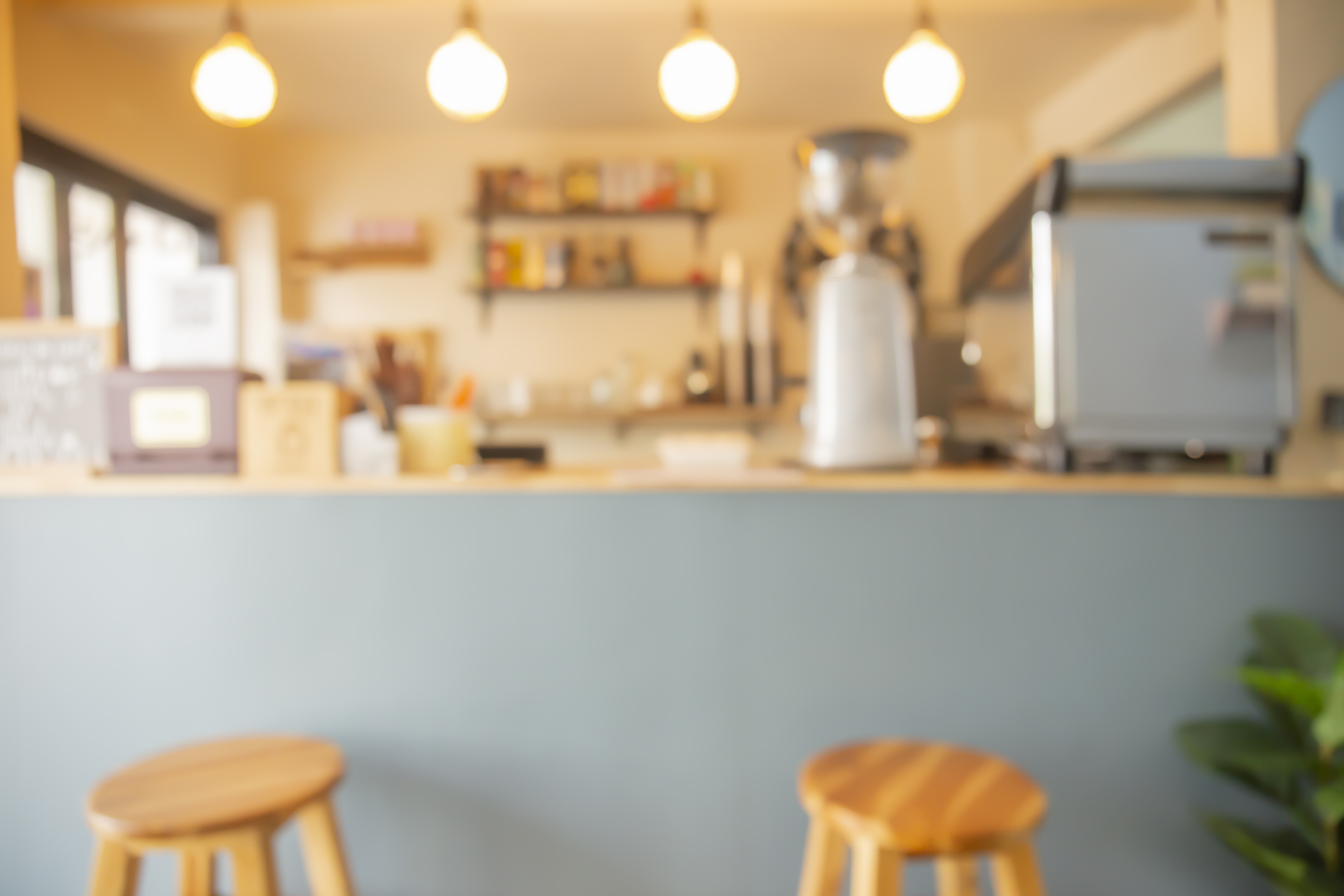 Abstract Blur Coffee Shop, Cafe, And Restaurant Counter For Back Blurred view of a small café or coffee shop counter with stools, warm lighting, and modern equipment.