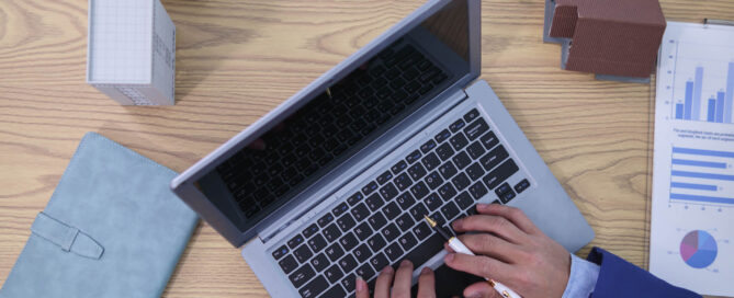 Business owner working on laptop reviewing short term business loan requirements with financial documents and charts on desk